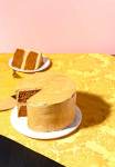 Pumpkin layer cake with slice cut out on a gold tablecloth with pink wall